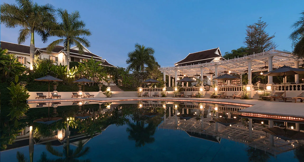 The Luang Say Residence's poolside terrace and colonial-style pergola at dusk