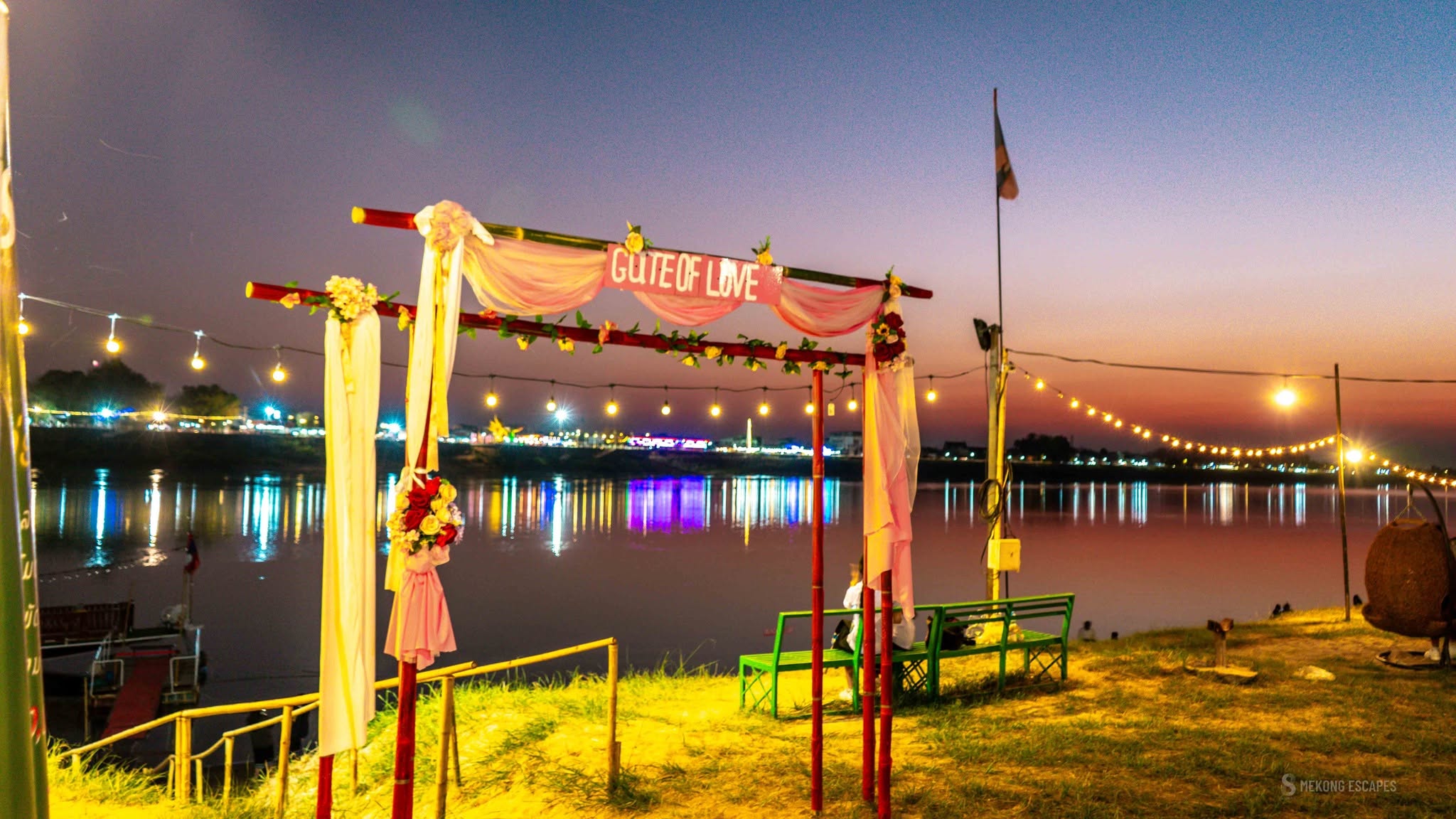 Vientiane, Laos: A Three-Day Pause in the Universe 3 Sunset over the Mekong River at Mekong Escapes beach in Vientiane, with string lights and the Gate of Love photo arch